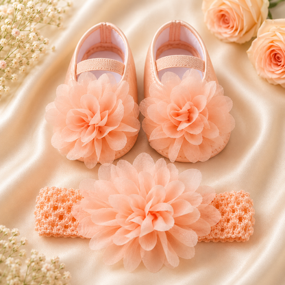 Pink baby shoes and headband with flowers on a satin surface surrounded by flowers.